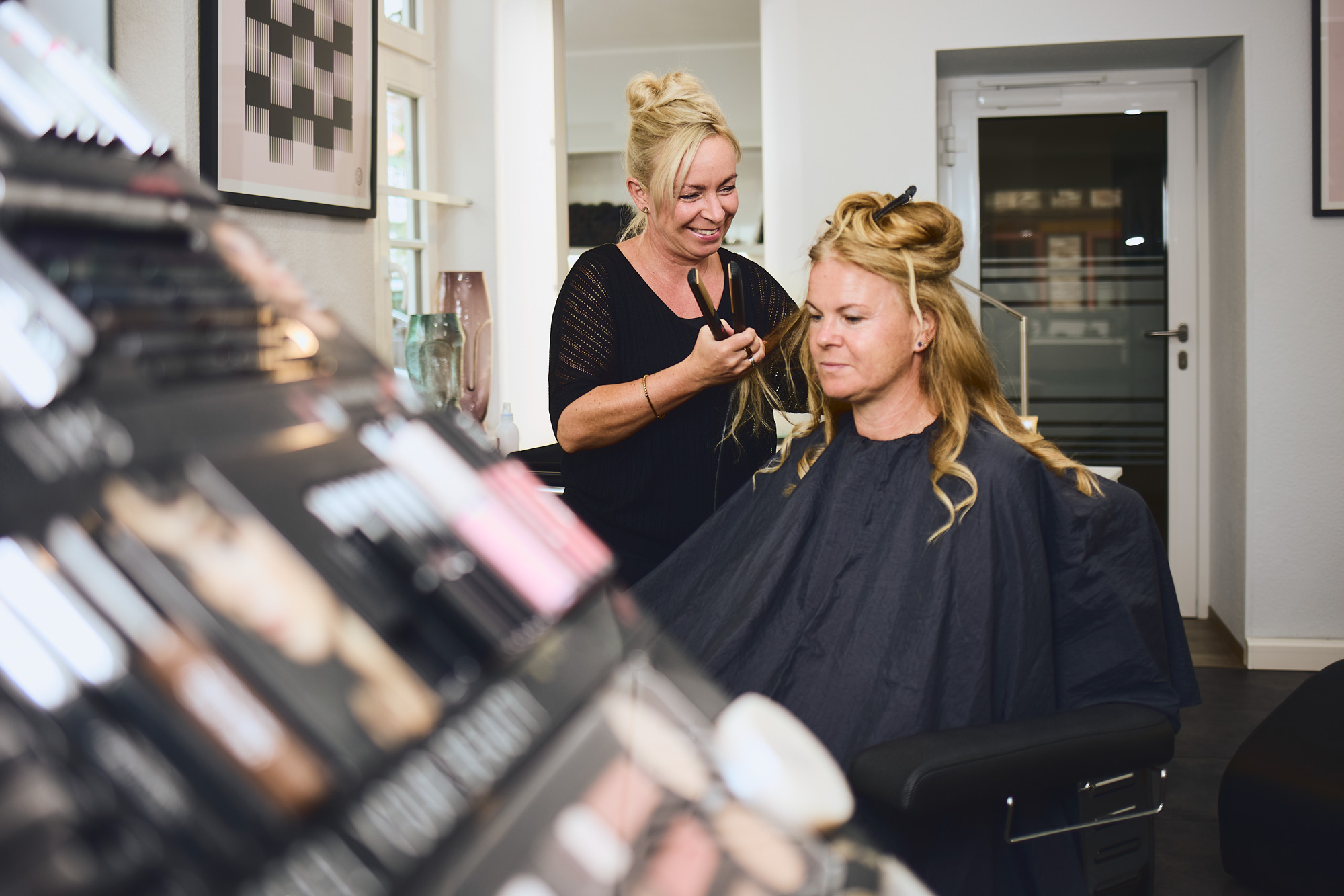 Karen Reinsdorf-Henze macht einer Kundin die Haare in ihrem Friseursalon in Wernigerode. Im Vordergrund zu sehen sind verschiedene Kosmetik-Assecoires.