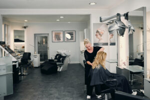 Weitwinkelaufnahme die den Innenraum des Friseursalon in Wernigerode zeigt. Im Zentrum Karen Reinsdorf-Henze bei der Arbeit.